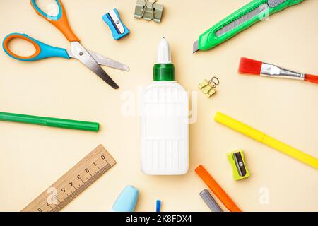 Composizione con bottiglia di colla e cancelleria diversa su sfondo colorato Foto Stock