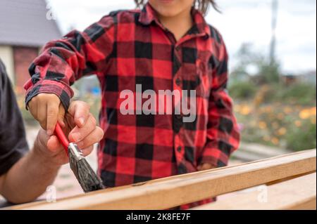 Mano dell'uomo che aiuta figlio con pennello Foto Stock
