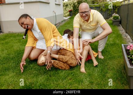 Genitori felici con bambini che giocano sull'erba in giardino Foto Stock