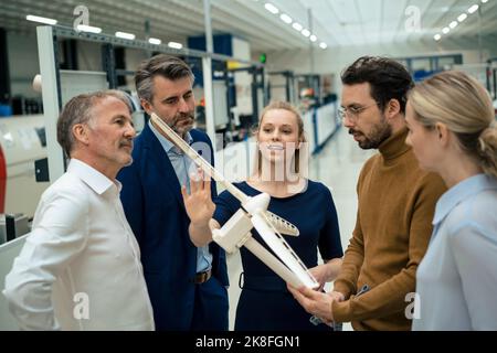 Uomini d'affari e donne d'affari discutono sull'industria delle turbine eoliche Foto Stock