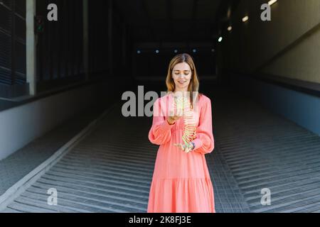 Donna sorridente che gioca con il giocattolo della molla elicoidale Foto Stock