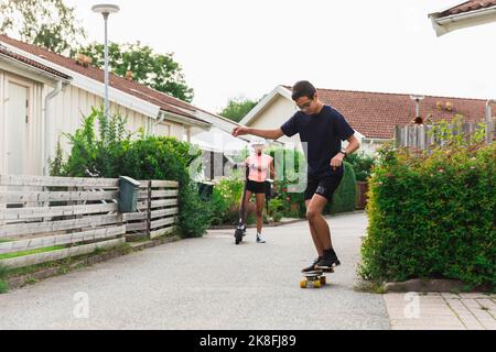 Fratello e sorella giocano e si divertono fuori casa Foto Stock