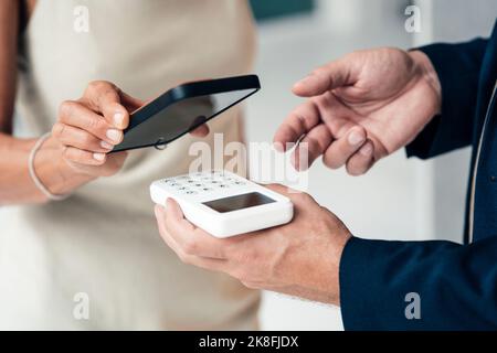 Mano del venditore che tiene il lettore della carta di credito con la donna che paga Foto Stock