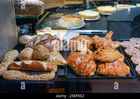 Panini dolci e pane di vario tipo e dolci più grandi sul retro del banco all'interno del negozio in Baviera Foto Stock