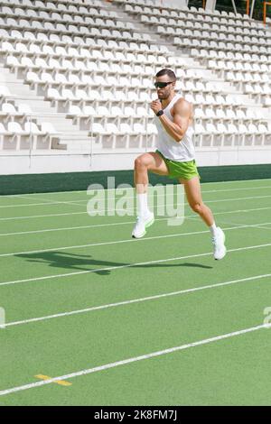 Uomo attivo che pratica la corsa sulla pista sportiva Foto Stock