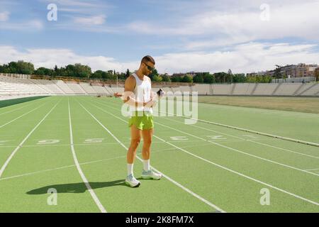 Atleta in piedi con bottiglia d'acqua sulla pista da corsa Foto Stock