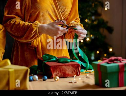 Donna taglio nastro sul regalo di Natale a casa Foto Stock