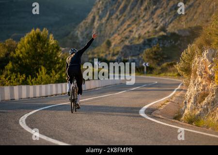 Ciclista con pedalata a mano su strada al passo della Costa Blanca ad Alicante, Spagna Foto Stock