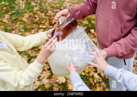 Mani di uomo e bambini che raccolgono rifiuti di plastica Foto Stock