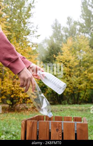 Mani dell'uomo che mette la bottiglia di plastica nel cestino Foto Stock