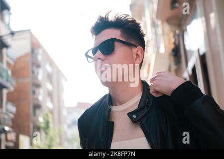Giovane uomo che indossa occhiali da sole davanti all'edificio Foto Stock