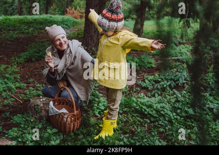 Felice nonna e figlia godendo raccogliere funghi nella foresta Foto Stock