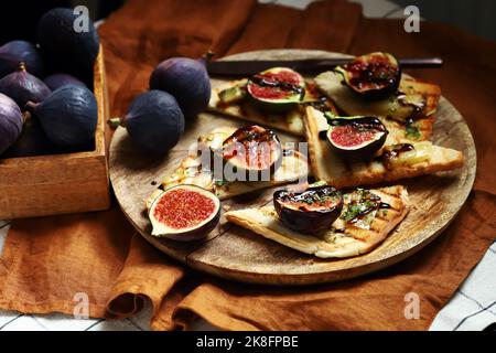 Pane tostato con formaggio, olio d'oliva, spezie e aceto balsamico. Bruschetta con fichi. Foto Stock