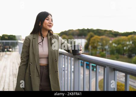 Donna premurosa con una tazza di caffè in piedi sulla terrazza Foto Stock