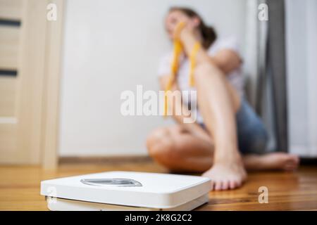 Scala bianca e depressione, donna sconvolta e triste con metro a nastro Foto Stock