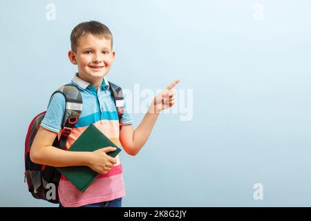 Ritorno a scuola. Felice studente di scuola elementare in eyeglasses hugging libro Foto Stock