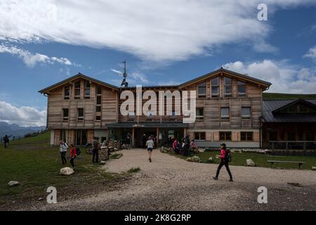 Il rifugio alpino Plattkofelhütte nelle Dolomiti all'Alpe di Siusi con escursionista di fronte. Foto Stock