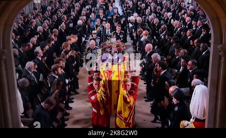 FUNERALI la Regina Elisabetta II il partito dei portatori funebri porta la bara di sua Maestà nel centro interno della Cappella di San Giorgio con la bandiera standard del Sovrano drappeggiata, la Corona Orb & Sceptre posta in cima. Re Carlo III segue la bara di sua madre insieme a membri stretti della Famiglia reale. 19th settembre 2022 Castello di Windsor Berkshire Regno Unito Foto Stock