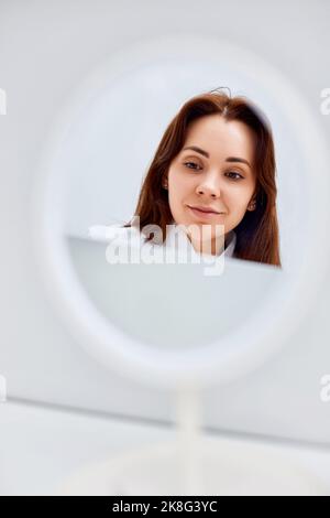 giovane donna felice che guarda nello specchio Foto Stock