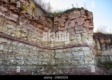 Ilmensky Glint è una formazione naturale, un monumento geologico sulla riva meridionale del lago Ilmen. Parete a strapiombo di rocce sedimentarie di diversi colori. Foto Stock