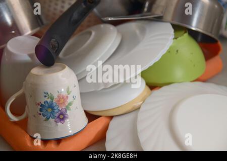 Primo piano di alcuni piatti che vengono drenati sulla panca in una cucina di famiglia dopo essere stati lavati a mano Foto Stock