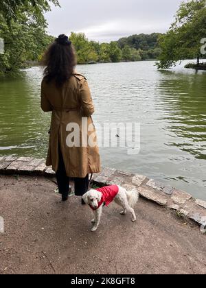 Donna con la sua piccola compagna guarda sul lago a Prospect Park, all'inizio dell'autunno a Brooklyn, New York. Foto Stock