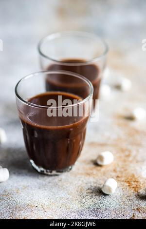 Cioccolata calda con mini marshmallow in vetro su fondo in cemento Foto Stock