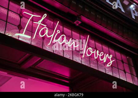Dal basso di un luminoso cartello rosa con illuminazione al neon che si trova sopra l'entrata del caffè Foto Stock