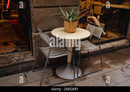 Street cafè nella città estiva con tavolo vuoto all'aperto. Pentola con piante, tavoli rotondi e sedie in legno nero Foto Stock