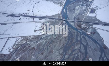 Dall'alto pittoresca vista del ponte che attraversa il lago calmo vicino alla catena montuosa innevata il giorno d'inverno in Islanda Foto Stock