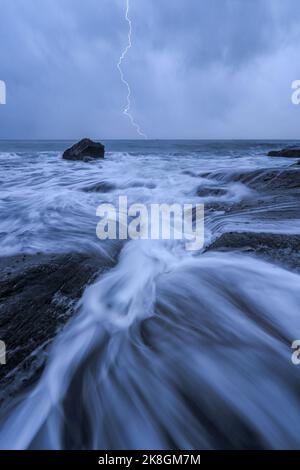 Vista spettacolare di un fulmine luminoso in un cielo cupo e nuvoloso lampeggiante sopra il mare durante le tempeste di tuoni nell'area dell'altopiano Foto Stock