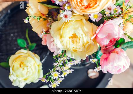 Vista dall'alto del bouquet fresco di fiori di rose messo in vaso sul tavolo. Primo piano di fiori rosa giallo. Arredamento estivo. Organizzazione di fiori Foto Stock