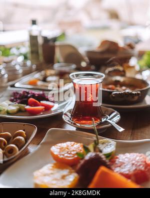 Da sopra bicchiere di tradizionale tè turco con vari piatti deliziosi e frutta servita al tavolo nel ristorante Foto Stock