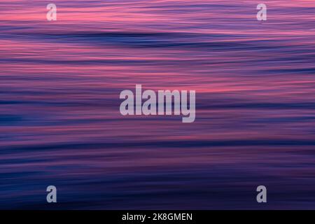 Sfondo a cornice di acqua di mare blu che ondita e riflette luce solare rosa Foto Stock