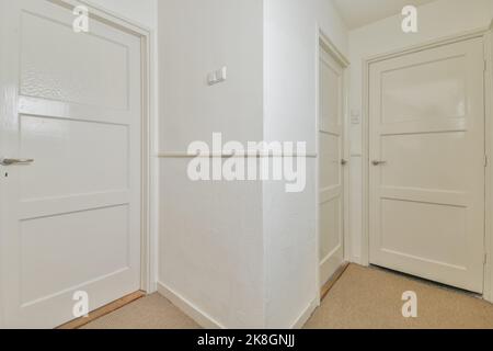 Porte chiuse bianche in corridoio chiaro con pareti bianche di un moderno appartamento Foto Stock