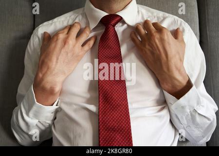 Uomo d'affari o manager che praticano l'EFT o la tecnica della libertà emotiva - toccando il punto del colarbone Foto Stock