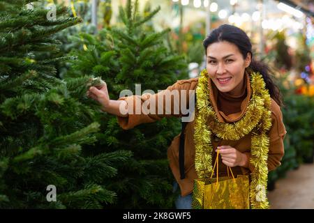 Cliente donna che acquista l'albero di abete al mercato di Natale Foto Stock