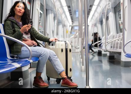 Passeggero donna che usa il telefono in una macchina della metropolitana Foto Stock