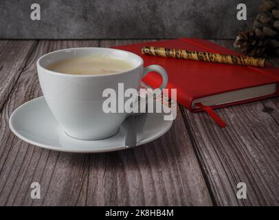tazza di caffè con notebook rosso su sfondo di legno Foto Stock