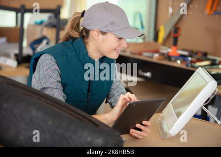 giovane donna che usa un tablet nella sua officina Foto Stock