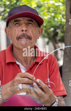 artigiano sulla strada facendo figurine di bicicletta con filo, figurine di metallo fatte a mano messico Foto Stock