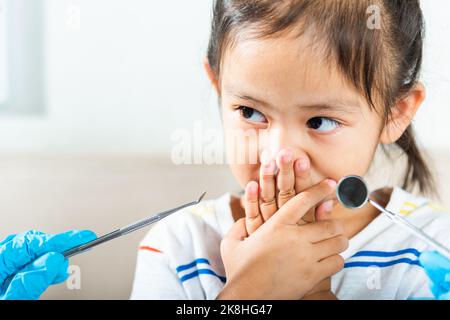 Esame dentale del bambino. Il medico esamina la cavità orale del bambino usa lo specchio della bocca per controllare la cavità dei denti ma la bocca della copertura della bambina non ha bisogno di controllare s Foto Stock
