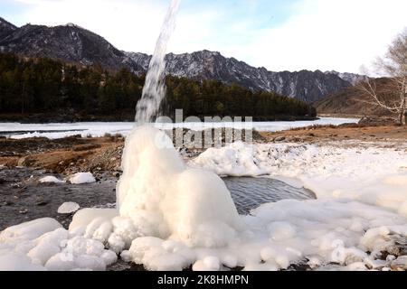 Un piccolo ruscello scorre su un blocco di ghiaccio in una pittoresca valle invernale circondata da montagne innevate sulle rive di un bellissimo fiume. Katun riv Foto Stock