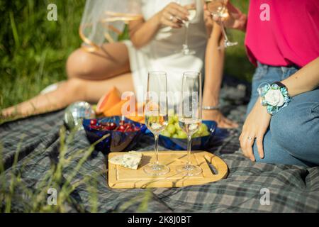 Picnic nella natura in estate. Bambine al picnic. Frutta e formaggio su tovaglia. Foto Stock