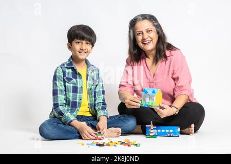 Ritratto di felice nonna indiana e nipote giocando con giocattoli colorati, isolato su sfondo bianco studio, nonna insegnamento maschio Grandchild, L Foto Stock