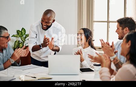 Quando il lavoro diventa una passione, youve già vinto. Un gruppo di uomini d'affari battono mentre si utilizza un computer portatile durante una riunione in un ufficio moderno. Foto Stock