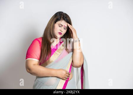 Ritratto di donna indiana sovrappeso che indossa saree isolato su sfondo bianco, asiatico stressato donna matura mano sulla testa. Foto Stock