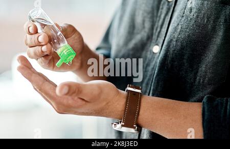 Semplici misure aiutano a ridurre al minimo la diffusione. Un uomo d'affari che usa l'igienizzatore per le mani per disinfettare le mani. Foto Stock