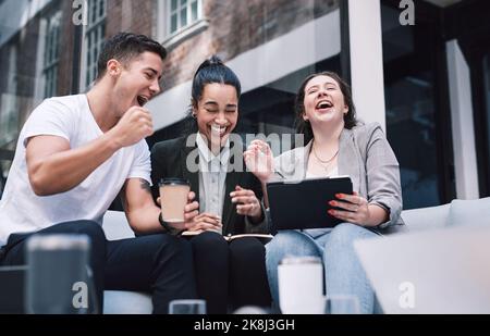 Con la grande passione si arriva a grandi profitti. Un gruppo di giovani imprenditori entusiasti che utilizzano un tablet digitale durante una riunione a una conferenza. Foto Stock