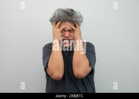 Ritratto di un furioso uomo anziano dai capelli grigi che urla, urla e gesta nella paura con mani e viso su sfondo isolato Foto Stock